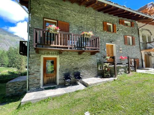a stone house with two chairs and a balcony at BOUQUE GEORGEOLINE in Rhêmes-Notre-Dame