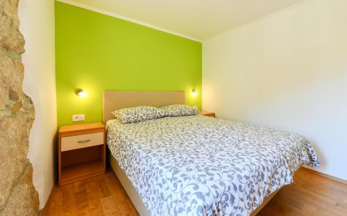 a bedroom with a bed and a green wall at Apartments Dolores Old Town in Mošćenička Draga
