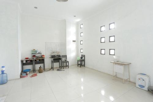 Habitación blanca grande con mesas y sillas. en SPOT ON 92782 Rumah Kost Kita Tarakan, en Tarakan