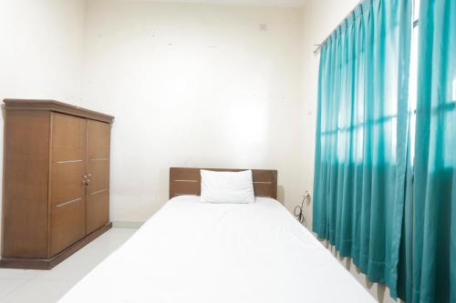 a bedroom with a bed and a wooden cabinet at Hotel O Rumah Kost Kita Tarakan in Tarakan