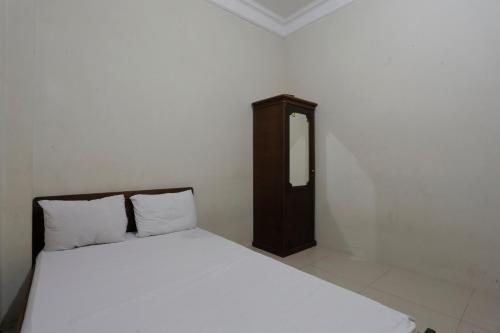 a bedroom with a white bed and a wooden cabinet at Hotel O Rumah Kost Kita Tarakan in Tarakan