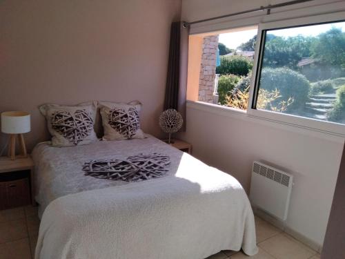 um quarto com uma cama e uma grande janela em Super nid douillet vue imprenable mer et piscine em Serra-di-Ferro