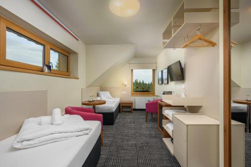 um quarto de hotel com duas camas e uma sala de estar em Hotel Premier- Adults Only em Bedřichov