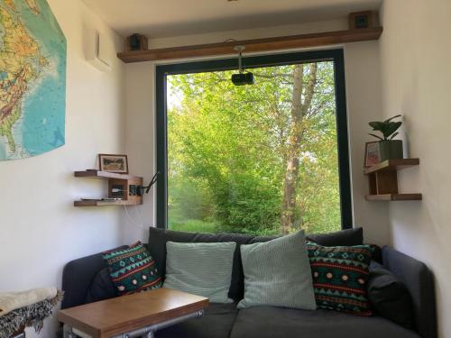 a living room with a couch and a large window at Tiny House im Seecontainer mit Parkplatz, Glasfaser, Netflix, Veranda und gehobener Ausstattung in Coburg
