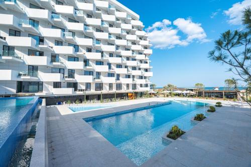 a building with a swimming pool in front of a building at Jo Residence Mamaia Nord in Mamaia Nord