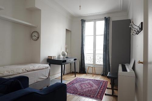 een slaapkamer met een bed, een bureau en een raam bij Eiffel Tower Appartment in Parijs