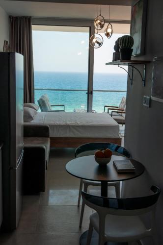 a room with a bed and a table and a view of the ocean at Seaview apartments in Ayios Elias