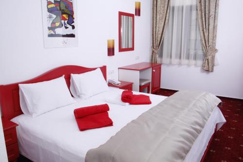 a bedroom with a white bed with red pillows on it at Hotel Exclusiv in Timişoara