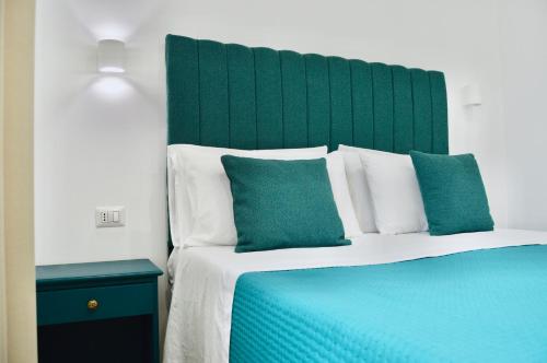 1 cama con cabecero verde y 2 almohadas azules en Novalis Rooms, en Porto Cesareo