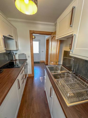 a kitchen with white cabinets and a sink and a stove at Skye-Fall in Drumfearn