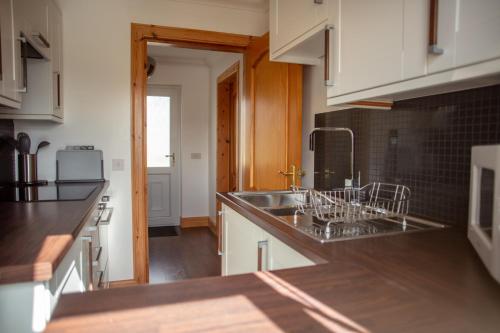 a kitchen with white cabinets and a sink at Skye-Fall in Drumfearn