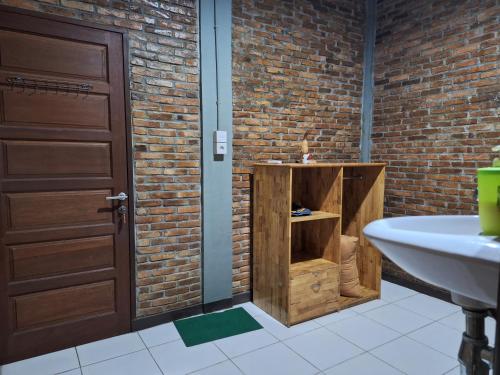a bathroom with a sink next to a brick wall at Bua Guest House in Medan