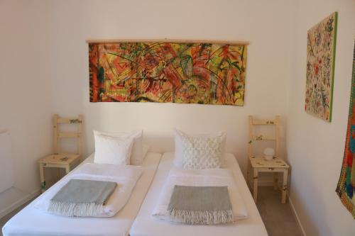 Habitación con 2 camas y una pintura en la pared. en Bedebike, en Óbidos