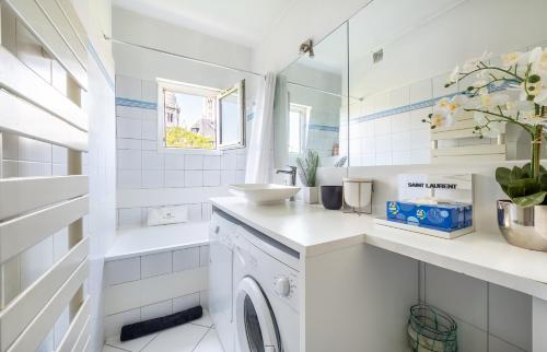 La salle de bains blanche est pourvue d'un lavabo et d'un lave-linge. dans l'établissement In front of The Sacre Cœur - 2 bedrooms with elevator, à Paris