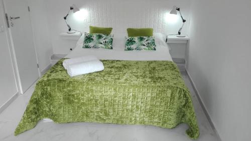 a bedroom with a bed with a green blanket and two lamps at JB House in Nazaré