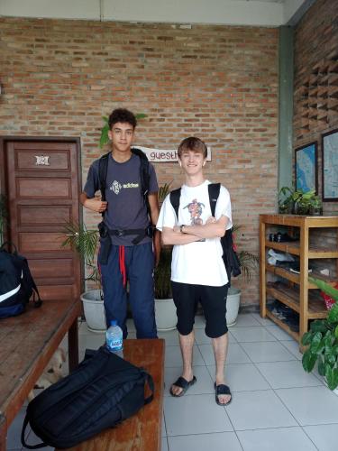 two young men standing next to a brick wall at Bua Guest House in Medan