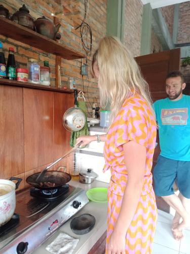 a man and a woman cooking food in a kitchen at Bua Guest House in Medan