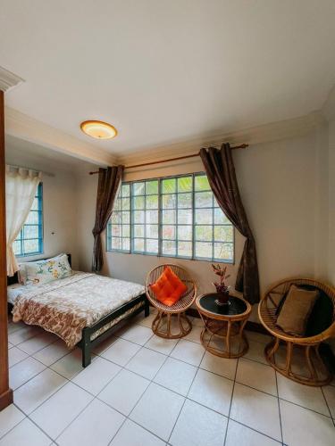 a bedroom with a bed and two chairs and a window at Shangri-La Heights Homestay in Kota Kinabalu