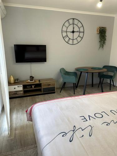 a living room with a tv and a table and a clock at STUDIO APARTMAN PAVIĆ in Vinkovci
