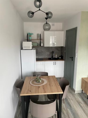 a kitchen with a wooden table and some chairs at Apartament Szałwiowy Dębina in Debina