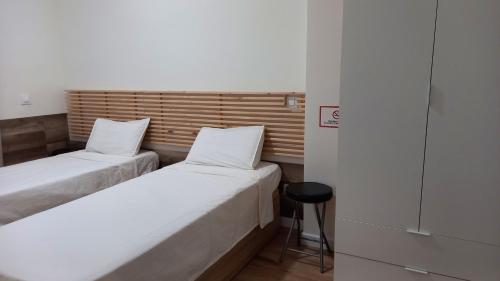 2 camas en una habitación pequeña con taburete en Cervante Apartment, en Alcalá de Henares