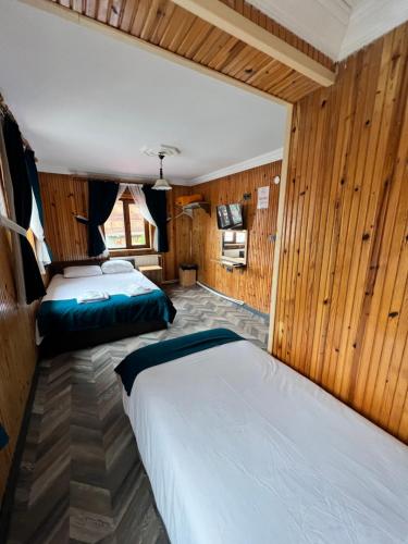 two beds in a room with wooden walls at Hayde otel in Çamlıhemşin