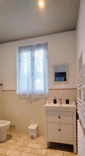 a bathroom with a sink and a toilet and a window at Villa Elvira in Ambra