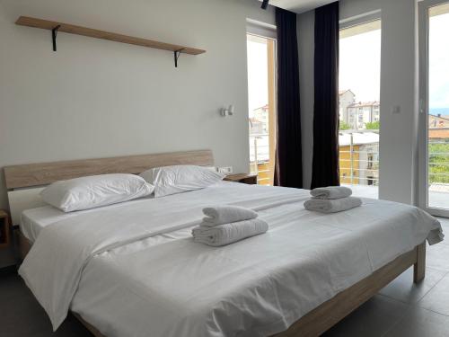 una camera da letto con un grande letto bianco con asciugamani di Apartments Joana a Ohrid