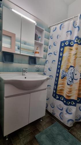 a bathroom with a sink and a shower curtain at Διαμέρισμα με θέα στη θάλασσα στα Λουτρά Ωραίας Ελένης in Loutra Oraias Elenis