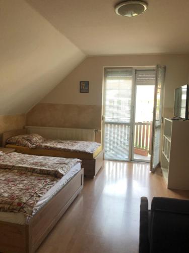 a bedroom with two beds and a balcony at Imre Apartman in Hajdúszoboszló