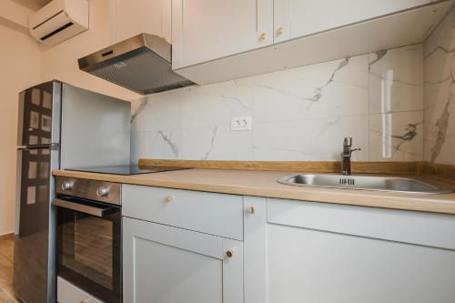 a kitchen with white cabinets and a sink at 3Level Apartments Kroatien in Umag