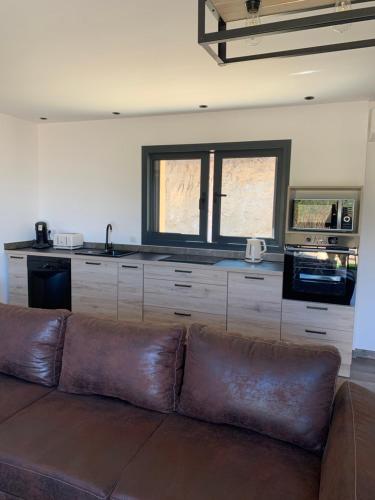 - un salon avec un canapé brun en face d'une cuisine dans l'établissement A casetta maison de plain pied, à Sartène