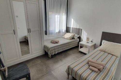 um pequeno quarto com 2 camas e um espelho em CASA CENTRO DEL PUEBLO CON PISCINA PRIVADA em Sant Vicenç de Montalt