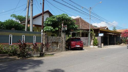 a red car parked in front of a house at Hotel O Coconut Island Homestay & ResortNearPantai Pulau Merah in Pasanggaran