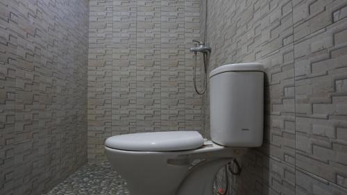 a bathroom with a toilet in a brick wall at OYO 92744 Coconut Island Homestay & Resort in Pasanggaran