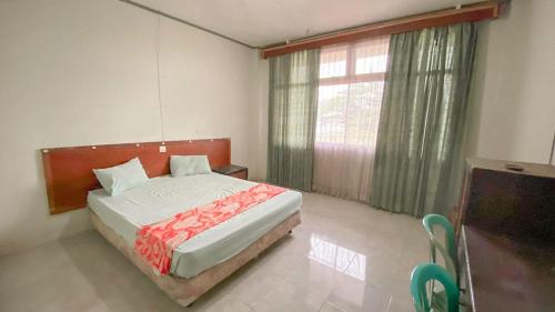 een slaapkamer met een bed en een groot raam bij OYO 92748 Hotel Tepian Batang Hari in Jambi