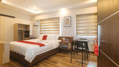 um quarto com uma cama e uma mesa com uma cadeira em RedDoorz Plus @ Bez Tower and Residences San Juan em Manila
