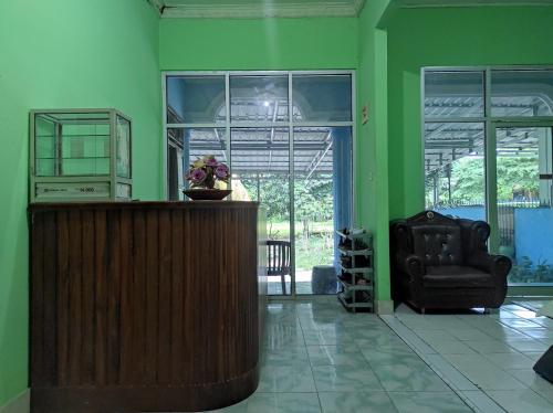 Cette chambre verte comprend une chaise et un bureau. dans l'établissement OYO 92724 Penginapan Syariah Al Syifa, à Kendari