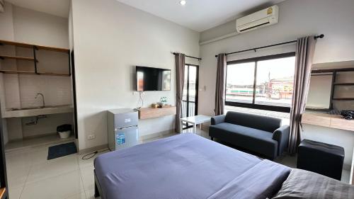 a bedroom with a bed and a chair and a window at Buathong Pool Villa in Ban Khung Taphao