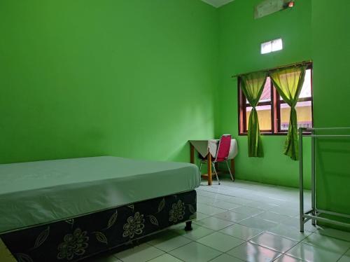 a green bedroom with a bed and a desk at Hotel O Penginapan Syariah Al Syifa in Kendari