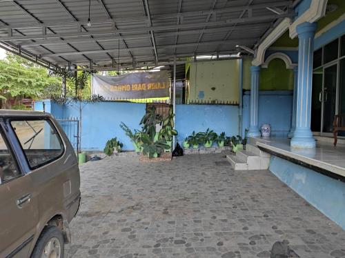 a car parked in front of a blue building at Hotel O Penginapan Syariah Al Syifa in Kendari