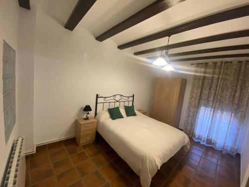 1 dormitorio con cama blanca y almohadas verdes en Agradable casa con chimenea interior y barbacoa., en Graja de Iniesta