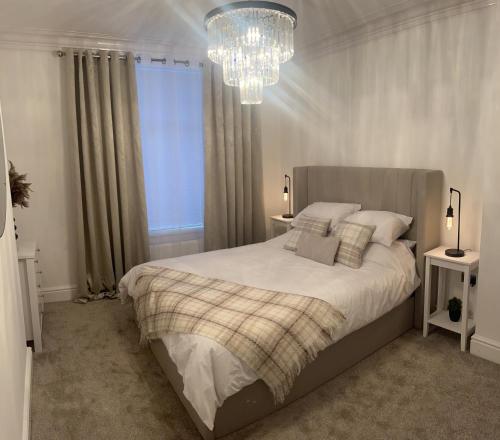 a bedroom with a large bed and a chandelier at Coastal Apartments No 2 in Seaham
