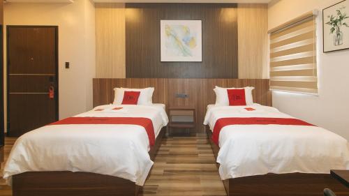 two beds in a hotel room with white and red sheets at RedDoorz Plus @ Bez Tower and Residences San Juan in Manila