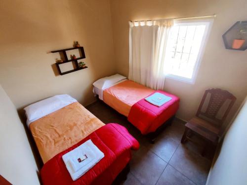Habitación con 2 camas, silla y ventana en Hotel AEROPUERTO Jujuy en Perico