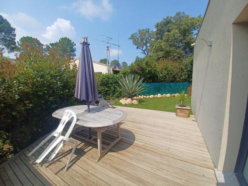 une table avec un parasol et deux chaises sur une terrasse dans l'établissement Mini villa a Lecci, Proche de la mer, à Lecci