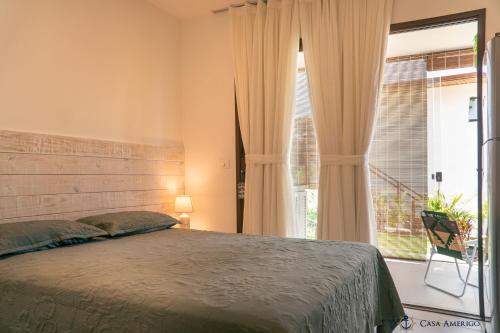 a bedroom with a bed and a large window at Casa Amerigo in Morro de São Paulo