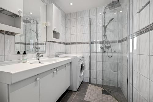 a white bathroom with a washing machine and a sink at 2 min to Bryggen - Rooftop - Office with 49" Screen in Bergen