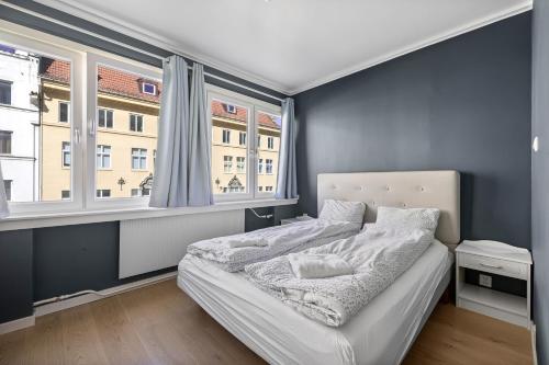 a bedroom with a bed and two windows at 2 min to Bryggen - Rooftop - Office with 49" Screen in Bergen