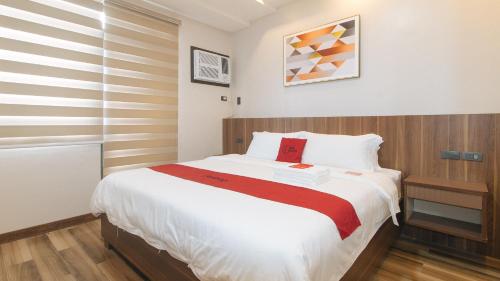a bedroom with a large white bed with red accents at RedDoorz Plus @ Bez Tower and Residences San Juan in Manila